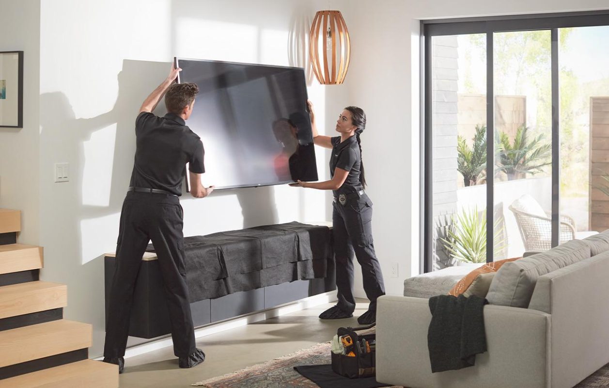How high to mount a TV - two installers mounting a flat-screen TV at eye level